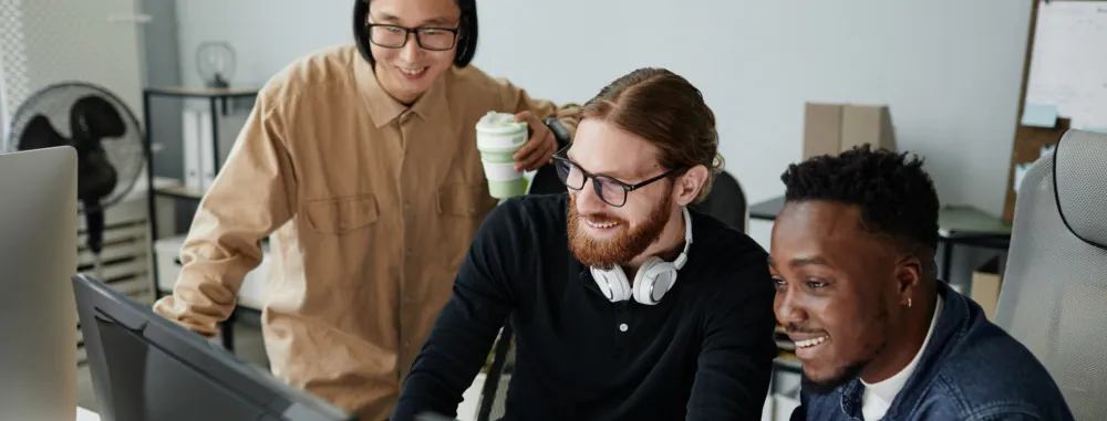 Three college students sit around a computer.