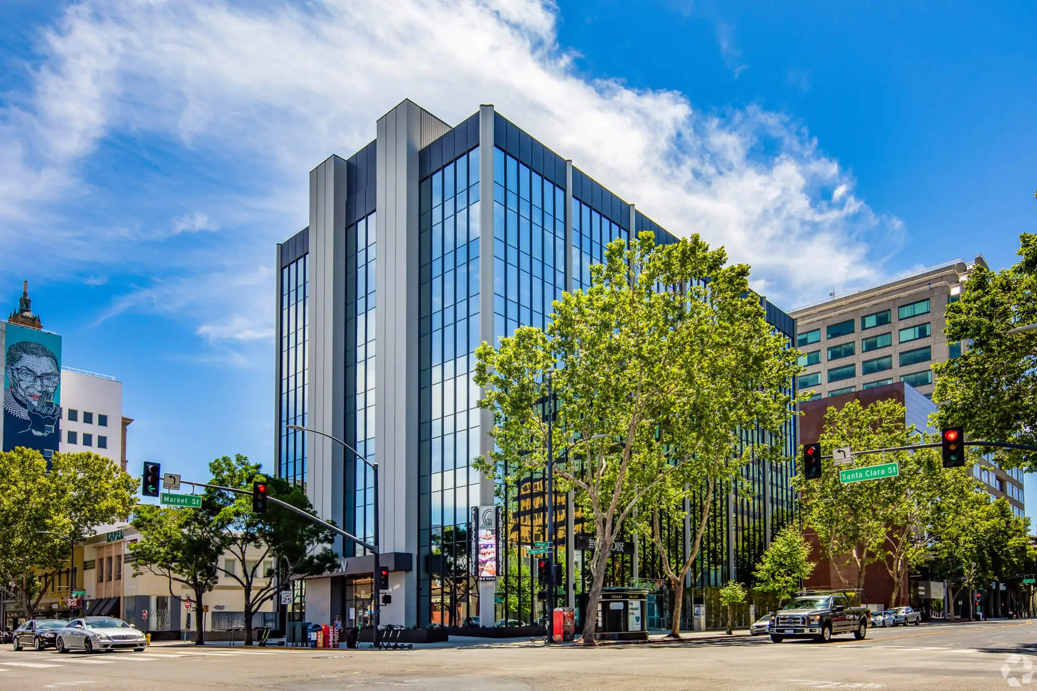 YuJa's Office, a modern glass building, stands gracefully with trees in the foreground against a clear blue sky.