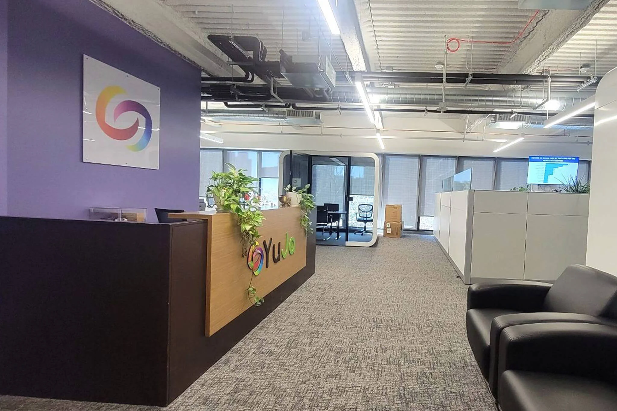 An office featuring a purple wall and sleek black chairs, designed for a modern and professional atmosphere at YuJa.