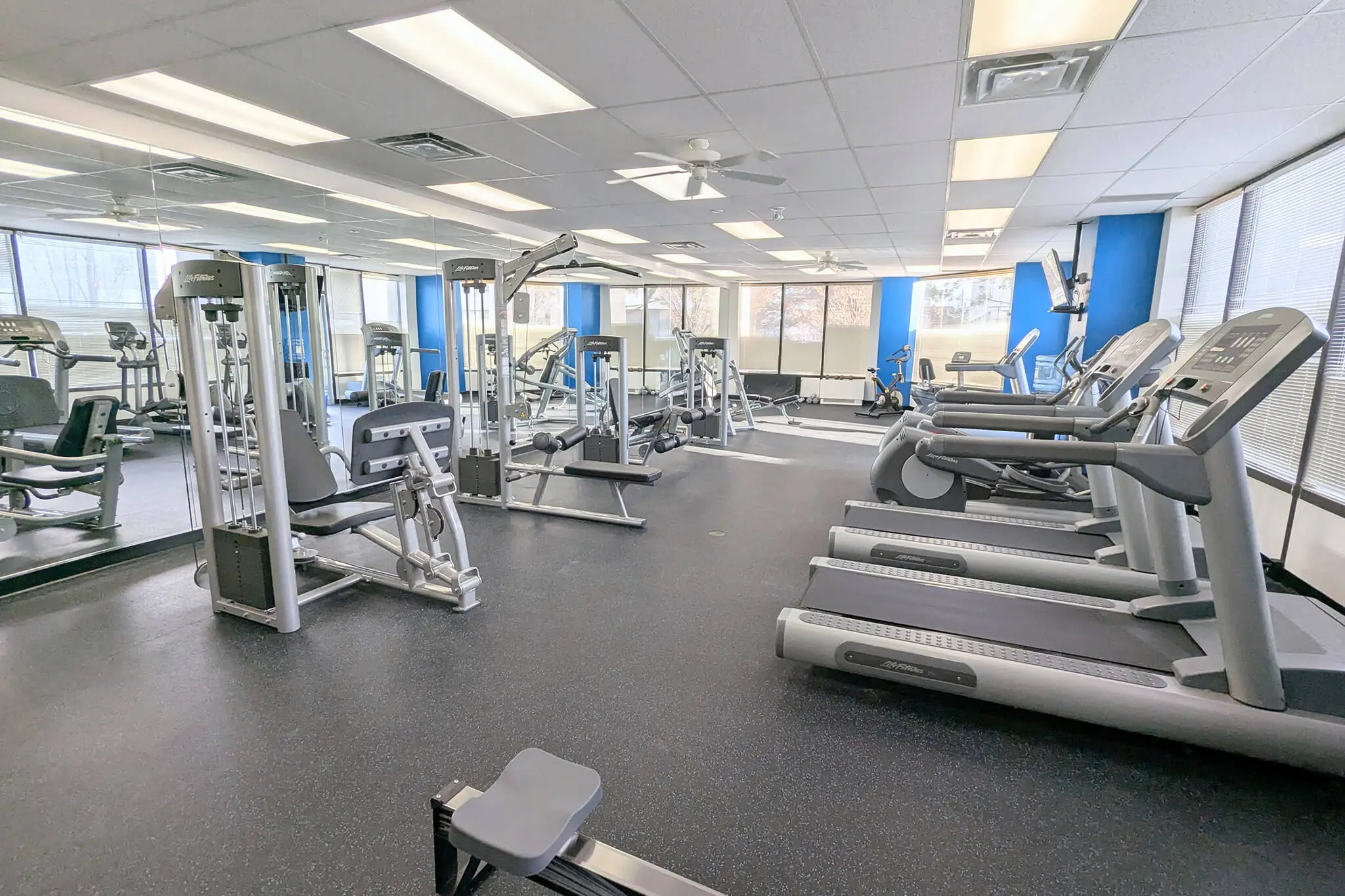 A gym room in YuJa's Office featuring treadmills and large mirrors for fitness activities.