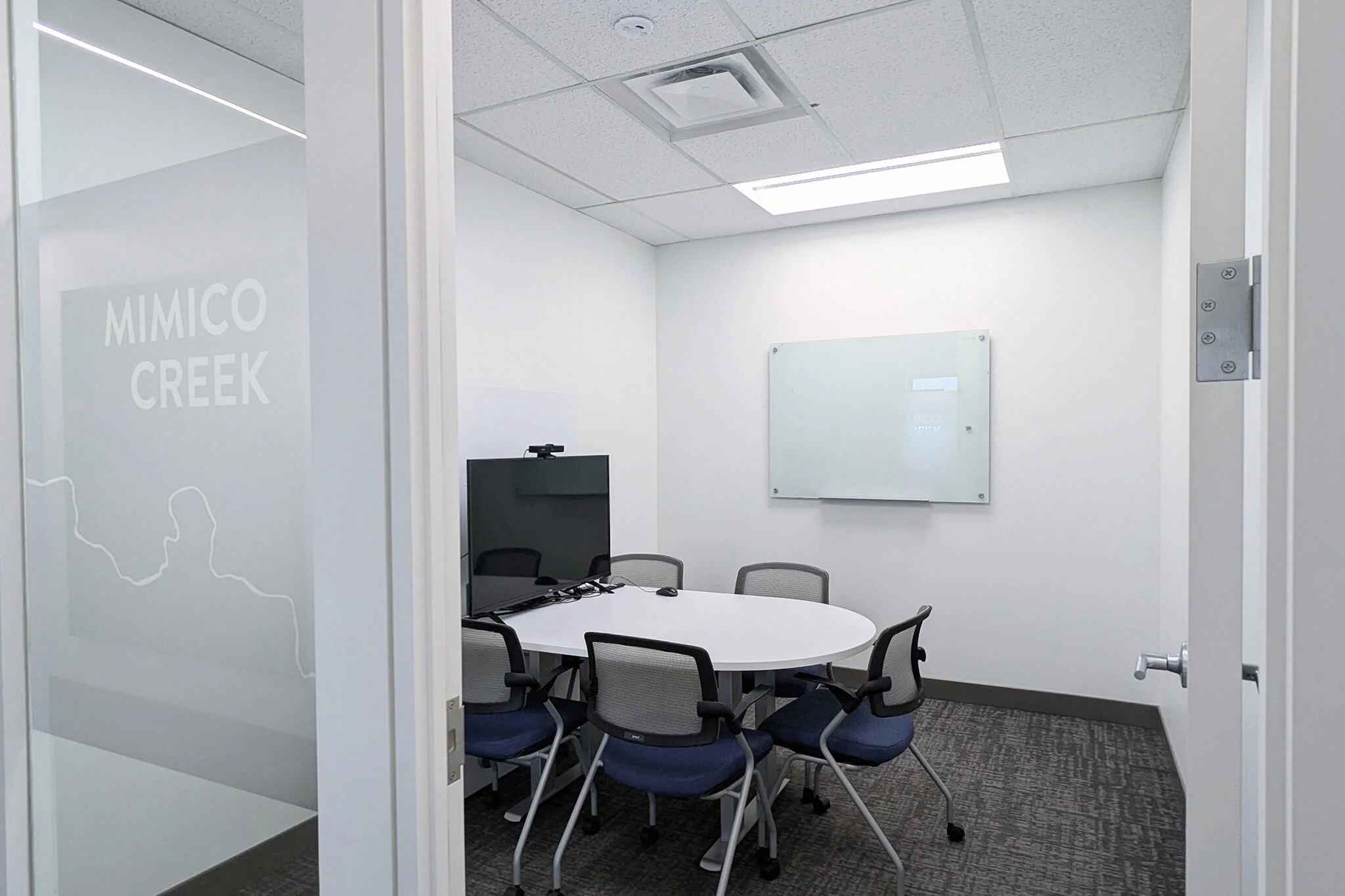 A conference room in YuJa's Office featuring a whiteboard and several chairs arranged for a meeting.