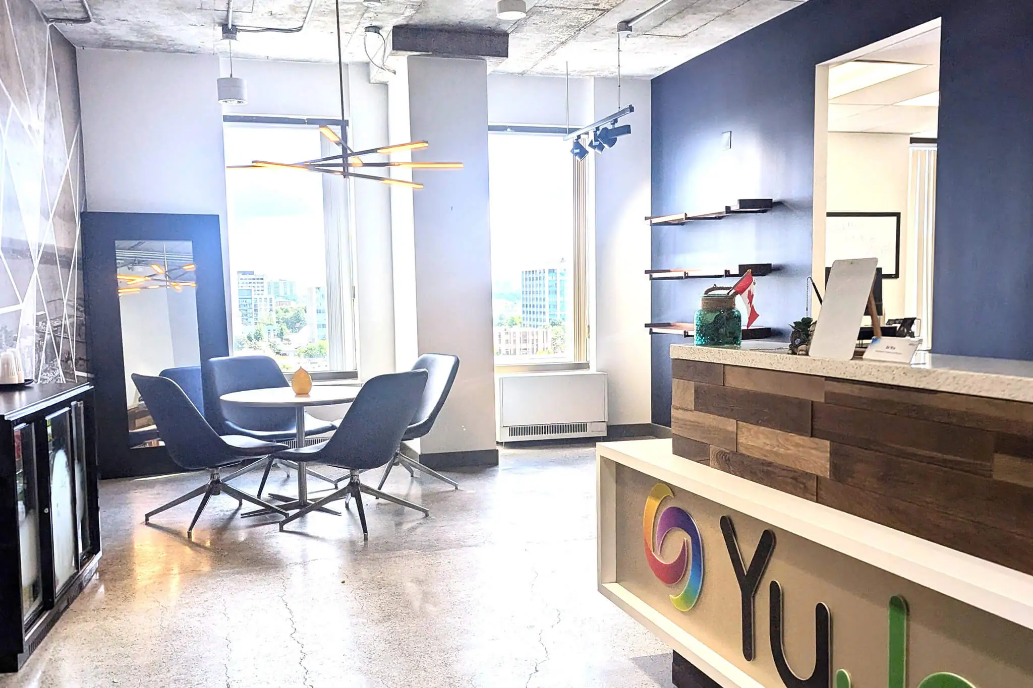 YuJa's office reception area with blue accent wall, eclectic lighting, and a branded desk.